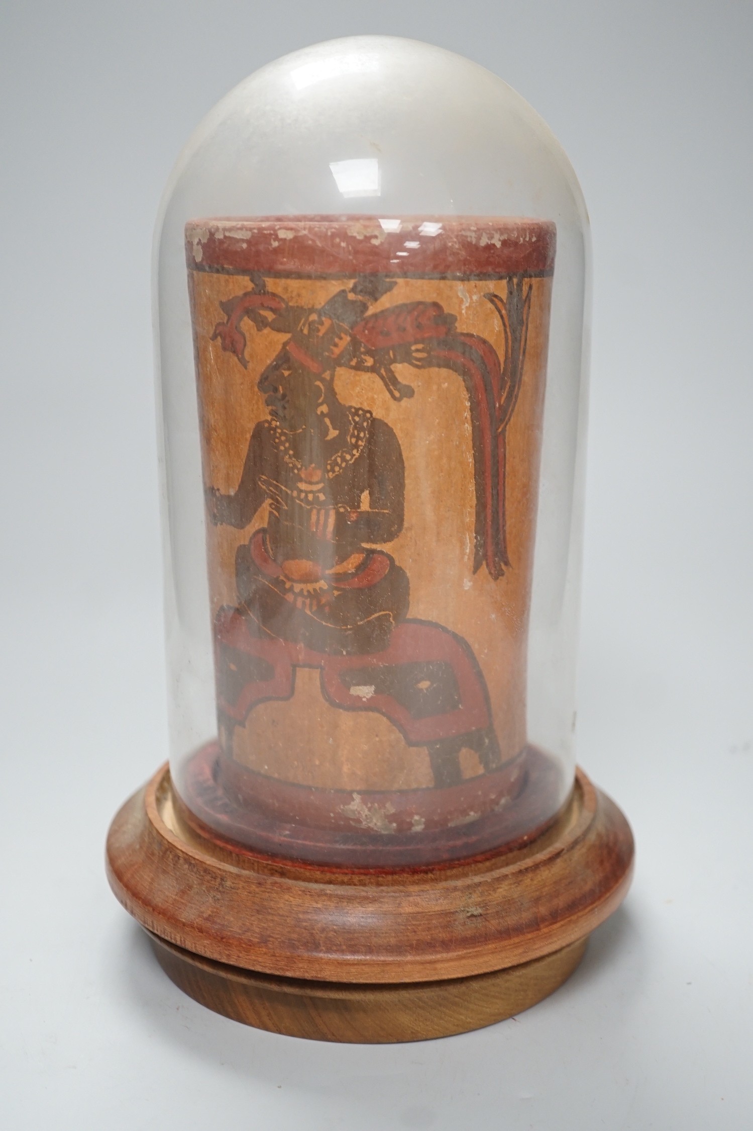A Mayan pigment painted terracotta cylindrical vessel, possibly 7th-9th century AD., 17.2cm high, under a glass dome with revolving wood stand, total height 26cm